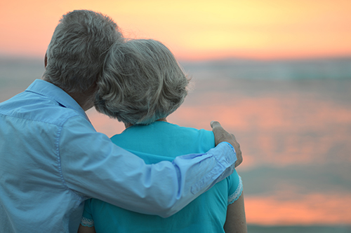 Elderly couple in an embrace watching a sunset